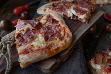 Homemade rustic pizza with italian ham, salami, mozzarella cheese on wooden background