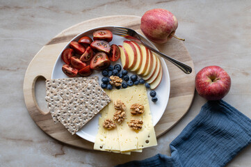 Simple Low carb meal with fiber crispbread, cheese, tomatoes, apples and walnuts on a plate