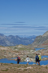 Fototapeta premium OZ-EN-OISANS, FRANCE, August 8, 2023 : Hikers walk on paths over the lakes of Grandes Rousses mountain range