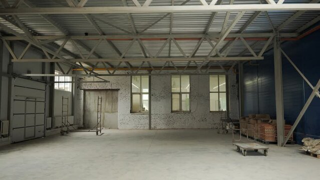 An empty bright industrial room with metal trusses and windows during the renovation. High quality 4k footage