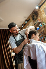 Little boy at the barber shop getting new haircut 