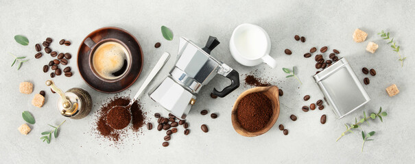 Flat lay with Moka pot, espresso cup, ground coffee, milk, sugar and coffee beans on a grey...