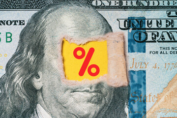 USD dollar banknote was torn at Benjamin Franklin 's eye with percentage sign for United of America...