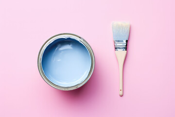 Top view of open new can of wall paint and painter brush on flat background, copy space, pink blue pastel colors palette.
