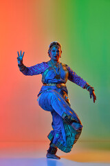 Beautiful indian woman dancing traditional dance in elegant blue dress against gradient studio background in neon light. Concept of beauty, fashion, India, traditions, choreography, art. Ad