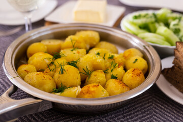 Toasted young potatoes with dill in metal skillet