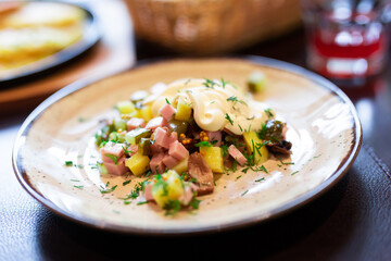 Fototapeta na wymiar Delicious potato salad with slices of ham and mushrooms close up