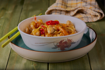Spicy chicken stir fry in a bowl with some chopsticks at the side.