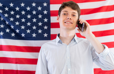 Young guy talking on phone on background of USA flag