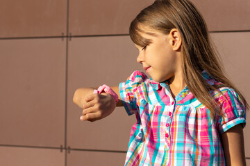 Caucasian little girl of 6 7 years looking at smartwatch to see time or to see who does calling