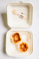 Mini Basque Burnt Cheesecake in paper food container. Top view and copy space on white table...