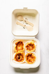 Mini Basque Burnt Cheesecake in paper food container. Top view and copy space on white table...