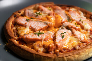 Delicious gourmet pizza with salmon on board with black table background. Homemade delicious pizza.