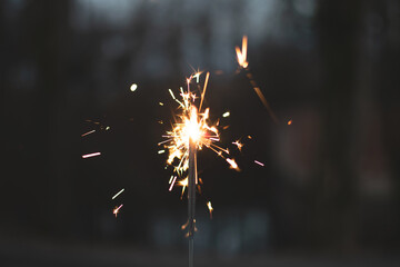 photography, sparkler close-up on a dark background, holiday lights	