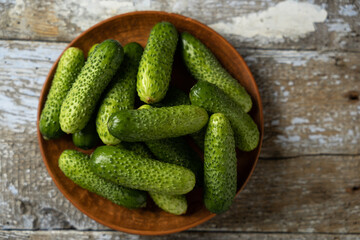 Green cucumbers on a plate, old wooden background, horizontal format, top view