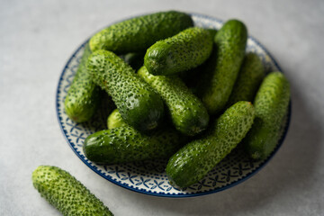 Fresh cucumbers on a plate, light gray stone background, horizontal format, macro