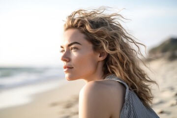 shot of a young woman looking over her shoulder while sitting on the beach
