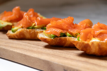 Smoked salmon with cream cheese and avocado slide on fresh croissants.