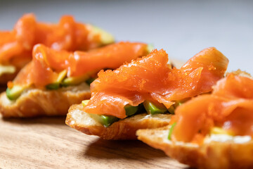Smoked salmon with cream cheese and avocado slide on fresh croissants.