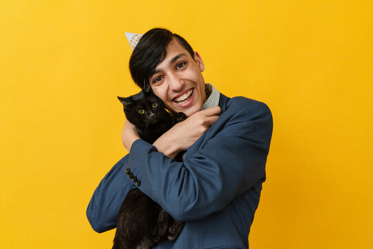 Happy man embracing cat against yellow background