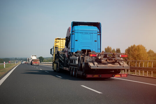 A side view of the towing truck with a vehicle having a mechanical steering engine problem. Emergency roadside assistance. A tow truck with a new semitrailer to transport to its owner.