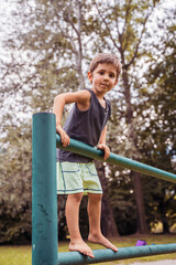 Fototapeta na wymiar smiling cute child climbing on a metal railing in a public park