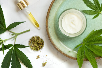 Obraz na płótnie Canvas CBD oil, tea and cream with hemp protein powder near green cannabis leaves