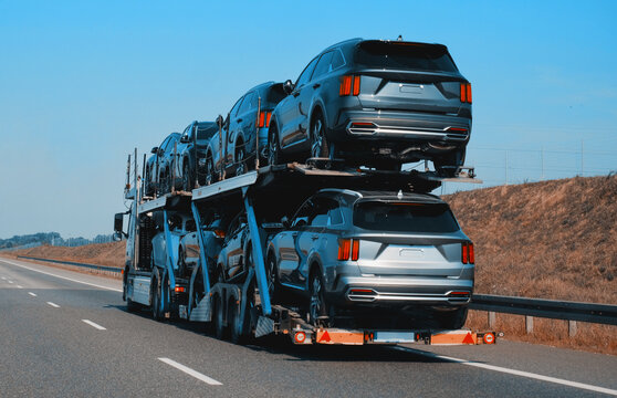 Car carrier trailer truck with brand new SUV cars for sale. New car delivery and shipping. Car transporter trailer loaded with many new cars for the customers. Two level modular hydraulic semi trailer
