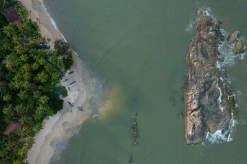 Beautiful beach scenery from above, Big rock with palm trees and green ocean view
