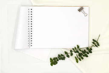 White notepad and green plant branch on white background with space for text, top view, flat lay