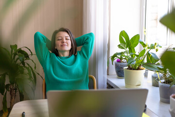 young female student relaxing with closed eyes, rejoicing over completion of project, done work, work-life balance, relieving stress. Female millennial relaxing at computer in home office