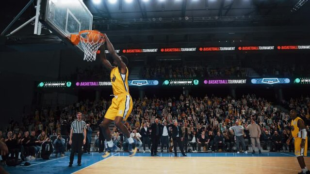 Slow Motion Replay of a Basketball Match in an Arena. Player Catching a Ball From a Teammate, Running to Score an Impressive Two-Point Goal with a Slam Dunk. Cinematic Sports Channel Footage