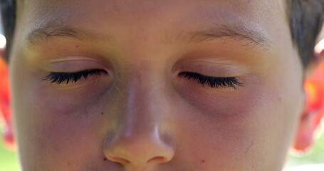 Obraz premium Boy face closing eyes close-up. Child macro eyes with eyes closed in meditation and contemplation