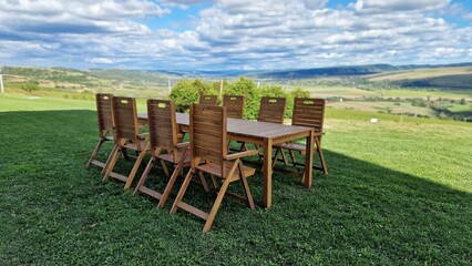Wooden table and chairs, on green meadow, in summer day.