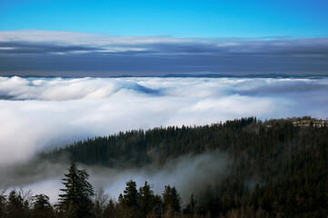 Fog on the slopes of mountain valleys. Sunny day, clear blue sky.