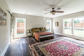 Spacious Bedroom with Large Windows and Traditional Decor Featuring Bed and Area Rug