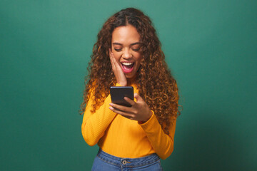 Young biracial woman reads text message shocked excited, green studio background