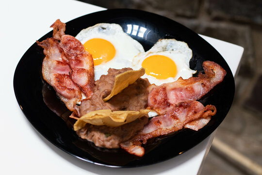 Huevos estrellados con frijoles y totopos y tocino frito 