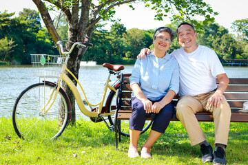 Happy smiling Asian elderly couple Sit in an outdoor park on a nice day. Health care in retirement. Health insurance for the elderly