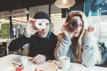 Two beautiful friends playing  with donuts