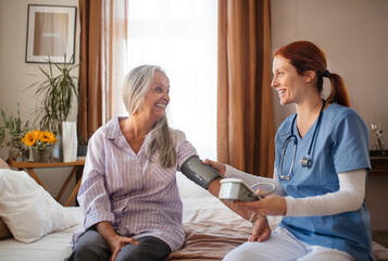 Nurse measuring an elderly woman's blood pressure at home.