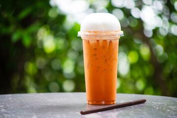Fresh thai tea with milk in transparent plastic in green nature background