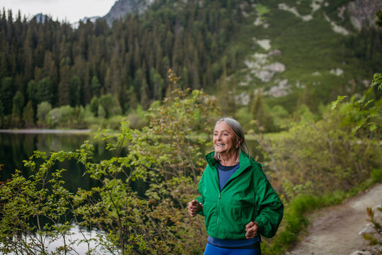 Senior woman running by the lake in the mountains.