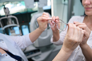 Optical dispenser handing prescription spectacles to client