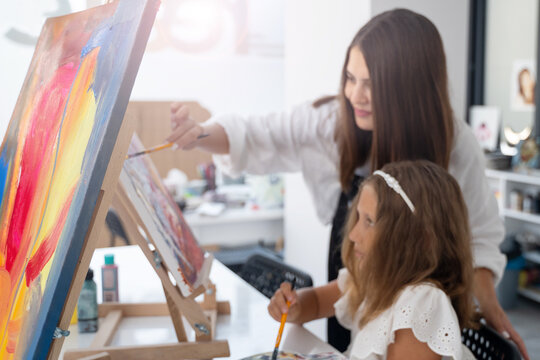 Teacher At Art School Helping Children in Art Class with painting.