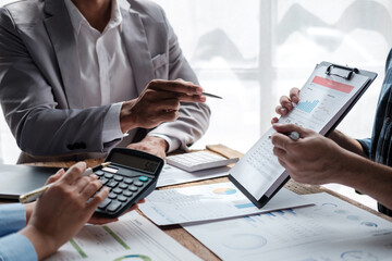 Diverse colleagues gather brainstorm discuss financial statistics at office meeting. finance,...