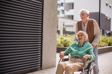 Fototapeta na wymiar Elderly man pushing his lovely wife in wheelchair.