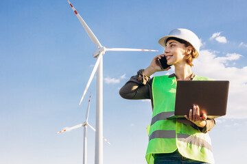 Woman with laptop having online conference by the windmill turbines