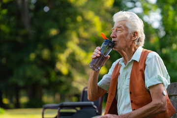 Senior man drinking water outdoor to better manage his diabetes. Elderly healthcare and diabetes in older people. 