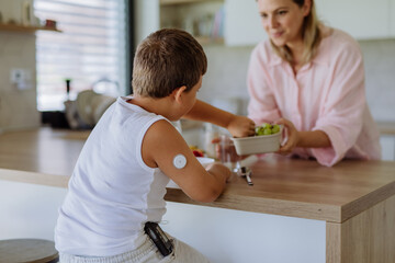 Diabetic boy with a continuous glucose monitor is careful with his diet.